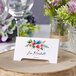 A close-up of a table with a floral Avery arched tent card.