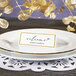 A white place card with a gold border on a plate.