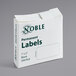 A white box of Noble permanent white labels with green text.