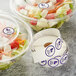 A roll of Point Plus Dairy Allergen labels on two plastic salad containers.