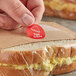 A hand putting a Point Plus Egg Salad label on a sandwich.