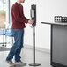 A man using a Lavex stainless steel hand sanitizer station.