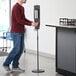 A man using a Lavex stainless steel automatic liquid sanitizing station.