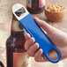 A hand using a Choice blue bottle opener to open a bottle of beer.