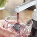 A person pouring Capora Blueberry Flavoring Sauce into a glass with ice.