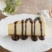 A slice of cheesecake with Capora chocolate sauce on top.