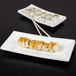 Two CAC Tokyia bone white rectangular porcelain platters with sushi on them.