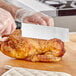 A person using a Mercer Culinary Duck Slicer to cut a chicken.