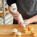 A person using a Choice Plastic Coated Canvas pastry bag to frost cupcakes.