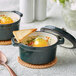 Two Valor bistro green enameled mini cast iron pots with food on a white table.