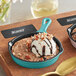 A Valor Aqua Sky enameled mini cast iron skillet with a scoop of ice cream, nuts, and chocolate sauce in it.