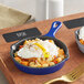 A Valor Galaxy Blue enameled mini cast iron skillet with poached eggs and potatoes.