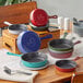 A green Valor enameled cast iron skillet on a table with other colorful skillets.