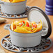 A Valor slate grey enameled cast iron pot filled with nachos and a lid on the table.