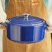 A person wearing gloves holding a Valor Galaxy Blue enameled cast iron Dutch oven with a lid.