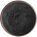 A black matte textured stoneware plate with a copper rim.
