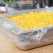 A pan of corn in a plastic bag on a stainless steel container.
