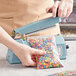 A person using a Thunder Group manual impulse bag sealer to seal a bag of candy.