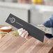 A person holding a Mercer Culinary black rectangular knife blade guard.