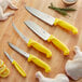 A Choice 5-piece knife set with yellow handles on a cutting board with lemon and herbs.