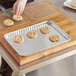 A gloved hand uses a spatula to transfer cookies from a Choice foil cookie sheet.