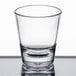 A Carlisle clear plastic shot glass with a small rim on a table.