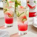 A glass of Monin watermelon and cucumber drink with ice and cucumber slices.