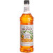 A Monin Premium Candied Orange Fruit Syrup bottle filled with orange liquid.