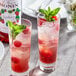 Two glasses of Monin raspberry drink with mint leaves.