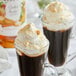 A glass cup of coffee with Monin Cookie Butter syrup and whipped cream.