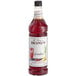 A Monin Premium Grenadine Flavoring Syrup bottle filled with red liquid.