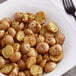 A plate of roasted potatoes seasoned with Lawry's Salt-Free Garlic and Herb Seasoning with a fork.