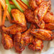 A plate of chicken wings with carrots and celery.