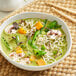 A bowl of green curry with vegetables and noodles.