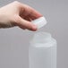 A hand holding a white plastic FIFO Innovations squeeze bottle with a lid.