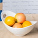 A 10 Strawberry Street white porcelain serving bowl with cut outs holding oranges on a table.