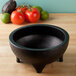 A black HS Inc. polypropylene molcajete on a wood surface with a tomato and lime inside.