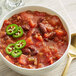 A bowl of Dei Fratelli seasoned diced tomatoes in chili with jalapenos and a spoon.