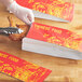 A person cutting a red and yellow Emperor's Select Chinese food bag with scissors.