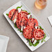 A white American Metalcraft rectangular melamine tray with tomatoes, feta cheese, and basil.