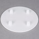 A white Wilton round cake separator plate with four holes in it.