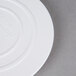 A white plastic Wilton cake separator plate on a gray surface.