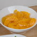 A bowl of peaches in a sauce.