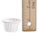 A white Solo paper souffle cup next to a ruler.