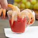 A Fineline clear plastic cup with a shrimp and sauce inside.