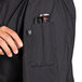A person's hand holding a Uncommon Chef Tempest Pro Vent women's chef coat pocket with a pen and a pocket knife.