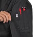 A woman's hand holding a red pen in the pocket of a black Uncommon Chef Napa chef coat.