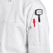 A person wearing a white Uncommon Chef coat with a pen in the pocket.