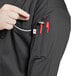 A Uncommon Chef long sleeve black chef coat with white piping and a pocket.