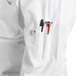 A person wearing a white Uncommon Chef long sleeve chef coat with a pen in the pocket.